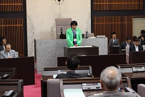 研修メンバーからのメッセージが書かれたジャンバーを着用し、研修の報告をする様子の写真